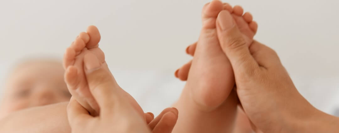 Mains prenant des pieds de bébé-Réflexologie